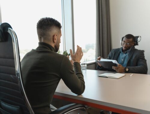 Een kandidaat die zich voorbereidt op een sollicitatiegesprek met notities en een laptop.